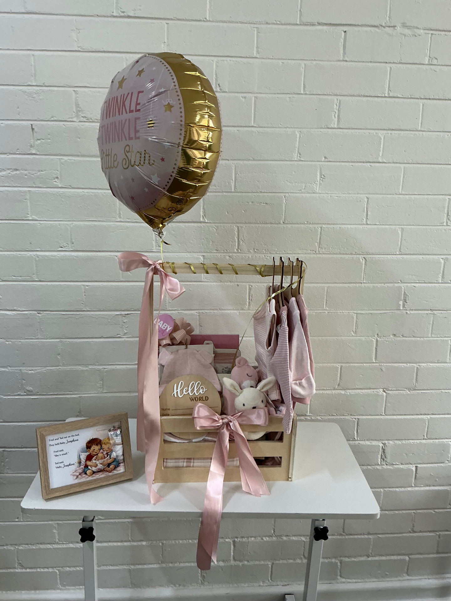 Bespoke pink baby shower basket on a hanging rail with balloon, ribbons, bunny and keepsake card
